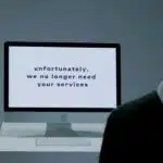 A computer screen displays the message: "unfortunately, we no longer need your services.