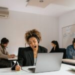 Four people with headsets work at desks with laptops in a bright, modern office environment.